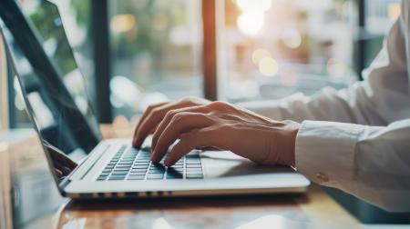 Person schreibt auf Tastatur eines Laptops